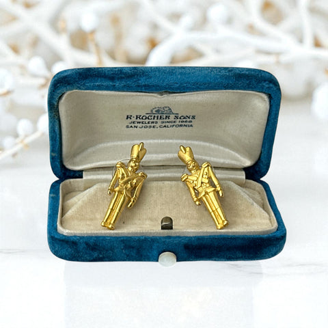 Gold tone vintage nutcracker earrings by JJ, featuring detailed toy soldier figures with tall hats and crossed arms; signed on the back with copyright symbol.