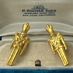 Gold tone vintage nutcracker earrings by JJ, featuring detailed toy soldier figures with tall hats and crossed arms; signed on the back with copyright symbol.
