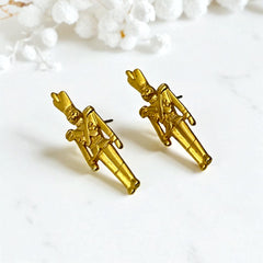 Gold tone vintage nutcracker earrings by JJ, featuring detailed toy soldier figures with tall hats and crossed arms; signed on the back with copyright symbol.