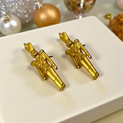 Gold tone vintage nutcracker earrings by JJ, featuring detailed toy soldier figures with tall hats and crossed arms; signed on the back with copyright symbol.