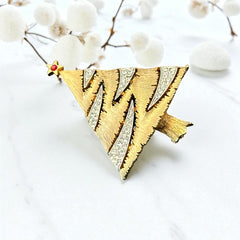 Vintage JJ Christmas tree brooch in textured gold-tone metal with silver-tone garlands paved in clear rhinestones and a red star at the top; signed JJ with copyright mark on the back, typical of 1980s holiday jewelry.
