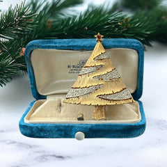 Vintage JJ Christmas tree brooch in textured gold-tone metal with silver-tone garlands paved in clear rhinestones and a red star at the top; signed JJ with copyright mark on the back, typical of 1980s holiday jewelry.