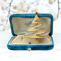 Vintage JJ Christmas tree brooch in textured gold-tone metal with silver-tone garlands paved in clear rhinestones and a red star at the top; signed JJ with copyright mark on the back, typical of 1980s holiday jewelry.