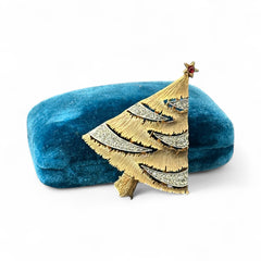 Vintage JJ Christmas tree brooch in textured gold-tone metal with silver-tone garlands paved in clear rhinestones and a red star at the top; signed JJ with copyright mark on the back, typical of 1980s holiday jewelry.