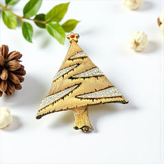 Vintage JJ Christmas tree brooch in textured gold-tone metal with silver-tone garlands paved in clear rhinestones and a red star at the top; signed JJ with copyright mark on the back, typical of 1980s holiday jewelry.
