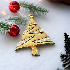 Vintage JJ Christmas tree brooch in textured gold-tone metal with silver-tone garlands paved in clear rhinestones and a red star at the top; signed JJ with copyright mark on the back, typical of 1980s holiday jewelry.