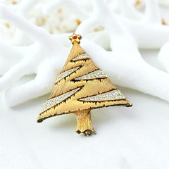 Vintage JJ Christmas tree brooch in textured gold-tone metal with silver-tone garlands paved in clear rhinestones and a red star at the top; signed JJ with copyright mark on the back, typical of 1980s holiday jewelry.