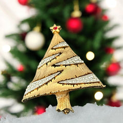Vintage JJ Christmas tree brooch in textured gold-tone metal with silver-tone garlands paved in clear rhinestones and a red star at the top; signed JJ with copyright mark on the back, typical of 1980s holiday jewelry.