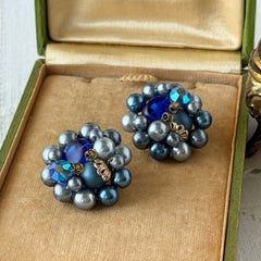 Vintage Japan blue faux pearl and rhinestone cluster clip‑on earrings with gold filigree backs, shown from multiple angles to highlight their wired construction and luminous beads.