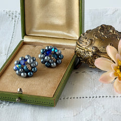 Vintage Japan blue faux pearl and rhinestone cluster clip‑on earrings with gold filigree backs, shown from multiple angles to highlight their wired construction and luminous beads.