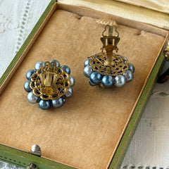Vintage Japan blue faux pearl and rhinestone cluster clip‑on earrings with gold filigree backs, shown from multiple angles to highlight their wired construction and luminous beads.