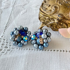 Vintage Japan blue faux pearl and rhinestone cluster clip‑on earrings with gold filigree backs, shown from multiple angles to highlight their wired construction and luminous beads.