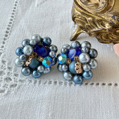 Vintage Japan blue faux pearl and rhinestone cluster clip‑on earrings with gold filigree backs, shown from multiple angles to highlight their wired construction and luminous beads.