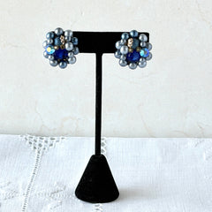 Vintage Japan blue faux pearl and rhinestone cluster clip‑on earrings with gold filigree backs, shown from multiple angles to highlight their wired construction and luminous beads.
