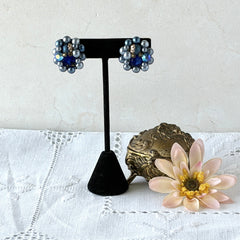 Vintage Japan blue faux pearl and rhinestone cluster clip‑on earrings with gold filigree backs, shown from multiple angles to highlight their wired construction and luminous beads.