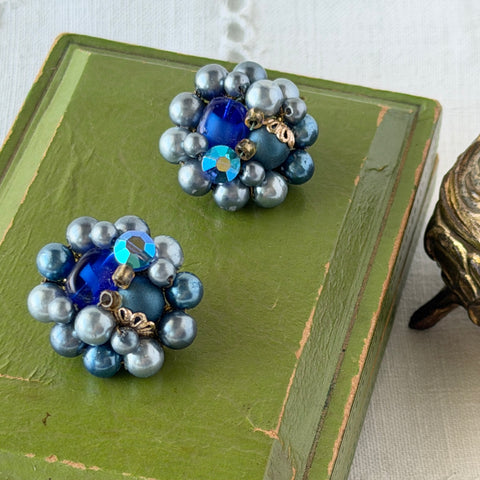 Vintage Japan blue faux pearl and rhinestone cluster clip‑on earrings with gold filigree backs, shown from multiple angles to highlight their wired construction and luminous beads.