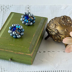 Vintage Japan blue faux pearl and rhinestone cluster clip‑on earrings with gold filigree backs, shown from multiple angles to highlight their wired construction and luminous beads.