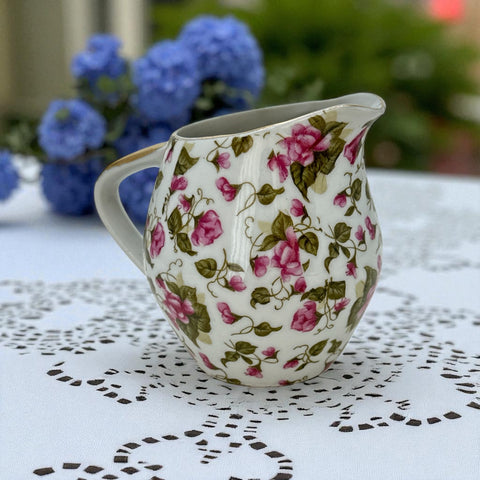 Vintage 1950s Japan porcelain creamer with pink chintz floral pattern, green leaves, and gold trim on rim and handle, marked Made in Japan