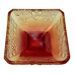 Vintage Jeannette Amberina Depression glass dish from the 1930s featuring a square footed base, an Acorn and Leaf pattern, and a color gradient from amber/yellow to red. Perfect as a candy dish or decorative piece, with a small chip on the rim adding character to its vintage charm.