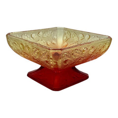 Vintage Jeannette Amberina Depression glass dish from the 1930s featuring a square footed base, an Acorn and Leaf pattern, and a color gradient from amber/yellow to red. Perfect as a candy dish or decorative piece, with a small chip on the rim adding character to its vintage charm.