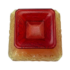 Vintage Jeannette Amberina Depression glass dish from the 1930s featuring a square footed base, an Acorn and Leaf pattern, and a color gradient from amber/yellow to red. Perfect as a candy dish or decorative piece, with a small chip on the rim adding character to its vintage charm.