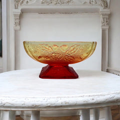 Vintage Jeannette Amberina Depression glass dish from the 1930s featuring a square footed base, an Acorn and Leaf pattern, and a color gradient from amber/yellow to red. Perfect as a candy dish or decorative piece, with a small chip on the rim adding character to its vintage charm.