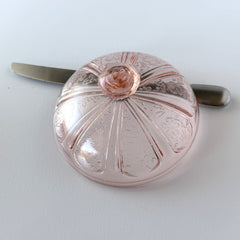 Vintage Jeannette Cherry Blossom pink Depression glass butter dish with embossed floral pattern, scalloped edges, and domed lid, shown in natural light on a white tabletop.