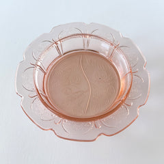 Vintage Jeannette Cherry Blossom pink Depression glass butter dish with embossed floral pattern, scalloped edges, and domed lid, shown in natural light on a white tabletop.