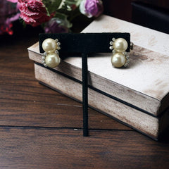 Vintage Jomaz clip-on earrings featuring two cream faux pearls accented with clear rhinestones in a silver-tone setting, signed on the back, shown in very good condition.