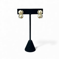 Vintage Jomaz clip-on earrings featuring two cream faux pearls accented with clear rhinestones in a silver-tone setting, signed on the back, shown in very good condition.