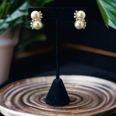 Vintage Jomaz clip-on earrings featuring two cream faux pearls accented with clear rhinestones in a silver-tone setting, signed on the back, shown in very good condition.