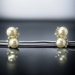 Vintage Jomaz clip-on earrings featuring two cream faux pearls accented with clear rhinestones in a silver-tone setting, signed on the back, shown in very good condition.