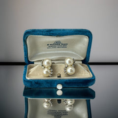 Vintage Jomaz clip-on earrings featuring two cream faux pearls accented with clear rhinestones in a silver-tone setting, signed on the back, shown in very good condition.