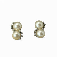 Vintage Jomaz clip-on earrings featuring two cream faux pearls accented with clear rhinestones in a silver-tone setting, signed on the back, shown in very good condition.