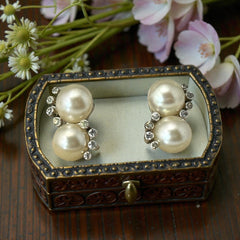 Vintage Jomaz clip-on earrings featuring two cream faux pearls accented with clear rhinestones in a silver-tone setting, signed on the back, shown in very good condition.