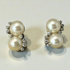 Vintage Jomaz clip-on earrings featuring two cream faux pearls accented with clear rhinestones in a silver-tone setting, signed on the back, shown in very good condition.