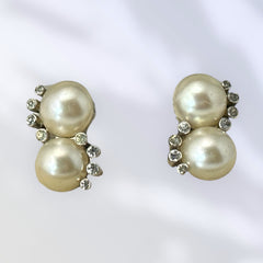 Vintage Jomaz clip-on earrings featuring two cream faux pearls accented with clear rhinestones in a silver-tone setting, signed on the back, shown in very good condition.