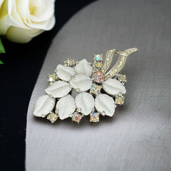 Vintage Jomaz floral spray brooch with molded milk glass leaves and aurora borealis rhinestones in silver tone setting, signed on reverse—1950s mid-century costume jewelry in excellent condition.