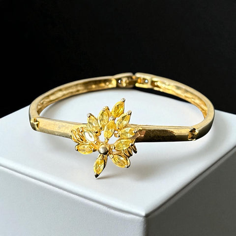 Vintage 1990s gold tone bracelet with curved links and a single jonquil marquise rhinestone flower centerpiece, elegant and gently worn.