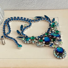 Vintage Juliana necklace with blue heliotrope oval stones and blue, green, and AB rhinestones in a silver‑tone setting.