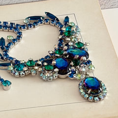 Vintage Juliana necklace with blue heliotrope oval stones and blue, green, and AB rhinestones in a silver‑tone setting.