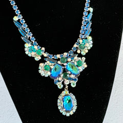 Vintage Juliana necklace with blue heliotrope oval stones and blue, green, and AB rhinestones in a silver‑tone setting.