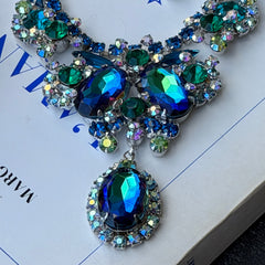 Vintage Juliana necklace with blue heliotrope oval stones and blue, green, and AB rhinestones in a silver‑tone setting.