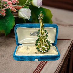 Vintage Juliana violin brooch in gold tone metal with green and peridot rhinestones, featuring layered construction and floral accents; verified design #3151 from the 1960s, shown from front and back.