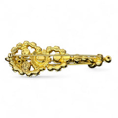Vintage Juliana violin brooch in gold tone metal with green and peridot rhinestones, featuring layered construction and floral accents; verified design #3151 from the 1960s, shown from front and back.