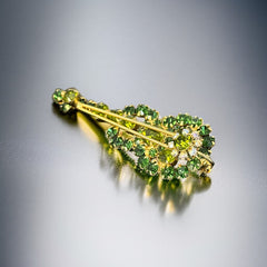 Vintage Juliana violin brooch in gold tone metal with green and peridot rhinestones, featuring layered construction and floral accents; verified design #3151 from the 1960s, shown from front and back.