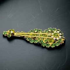 Vintage Juliana violin brooch in gold tone metal with green and peridot rhinestones, featuring layered construction and floral accents; verified design #3151 from the 1960s, shown from front and back.