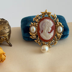 Vintage KJL for Avon gold tone cameo brooch pendant with resin cameo, faux pearls, clear rhinestones, and ornate detailing.