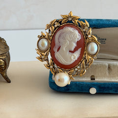 Vintage KJL for Avon gold tone cameo brooch pendant with resin cameo, faux pearls, clear rhinestones, and ornate detailing.