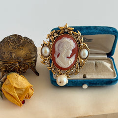 Vintage KJL for Avon gold tone cameo brooch pendant with resin cameo, faux pearls, clear rhinestones, and ornate detailing.